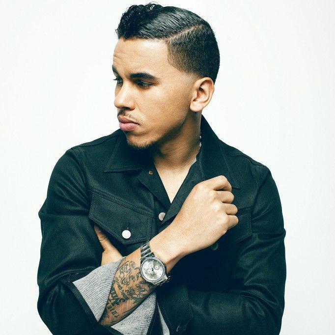 Man with tatoos looking off to the side with one arm up and the other folded